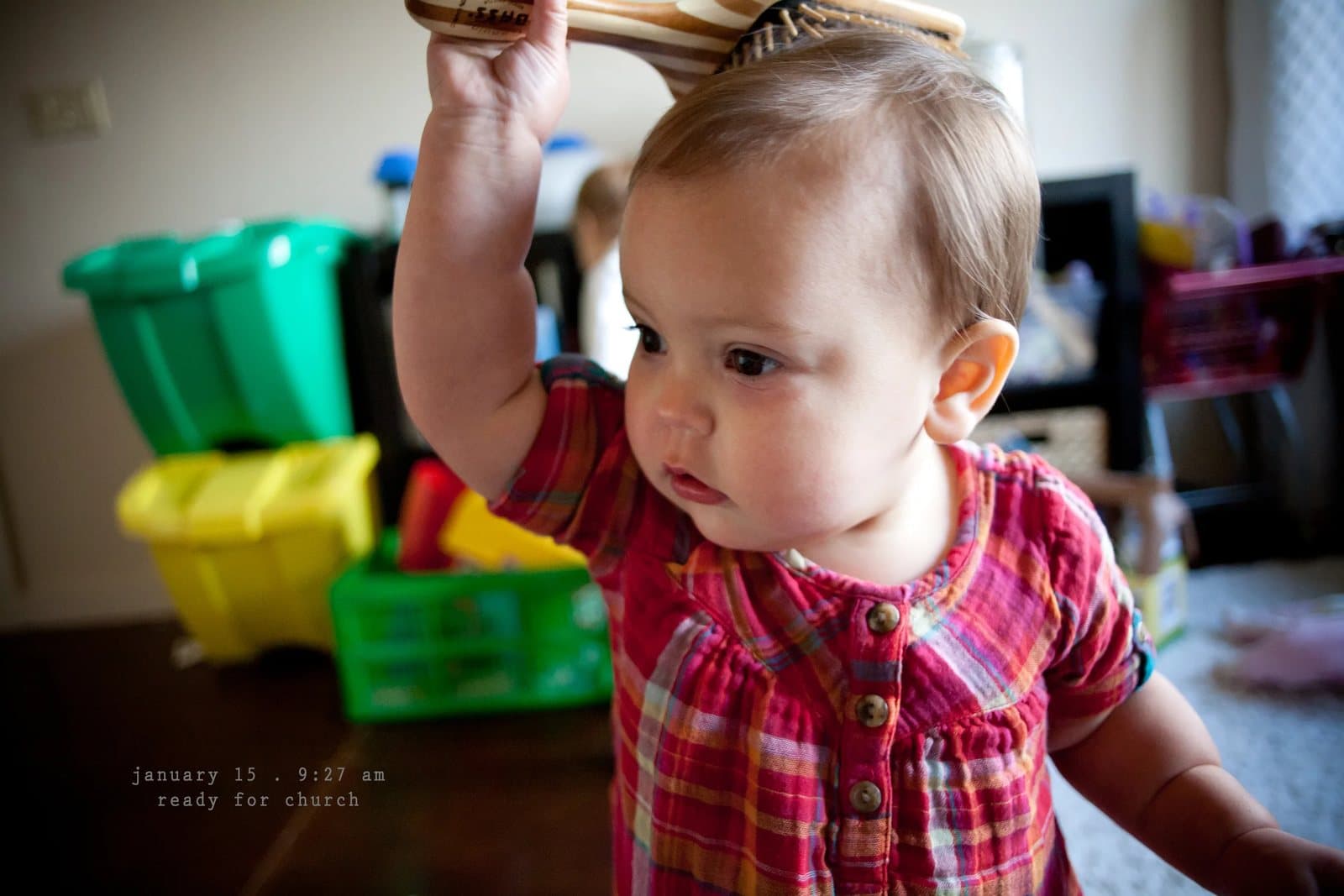 An adult brushes a baby girl's hair in a playroom, captioned ready for church.