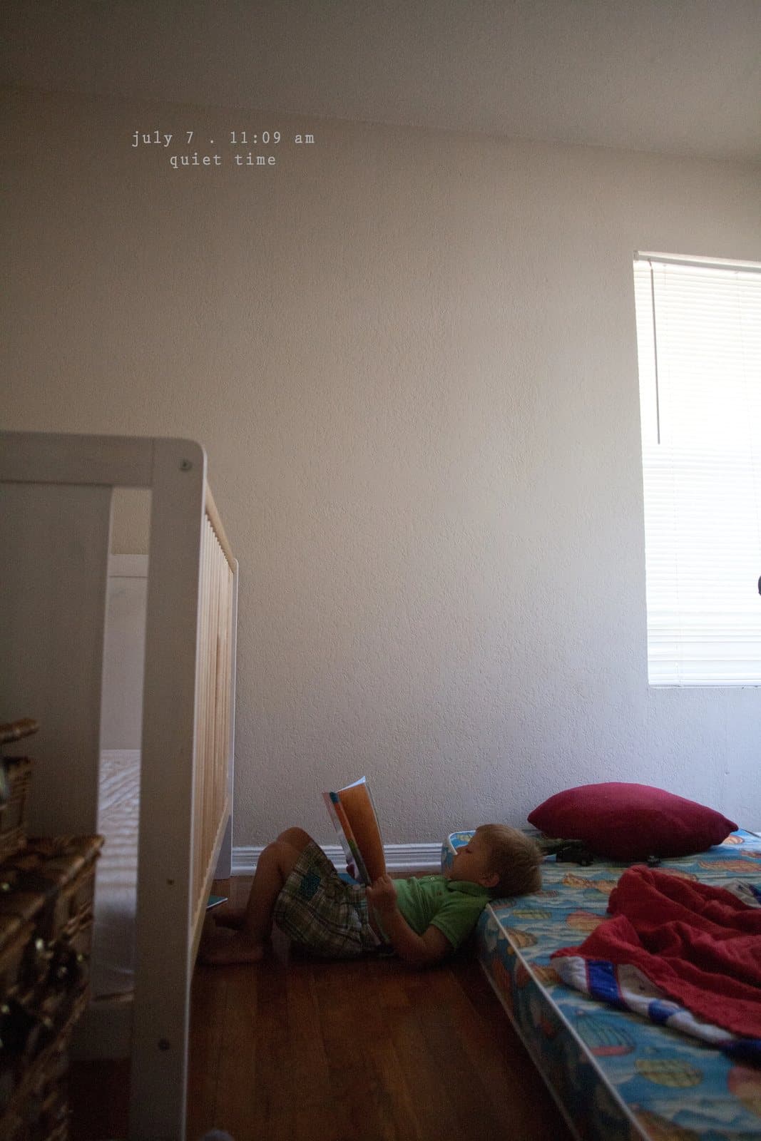 A child reads a book lying on a mattress in a bare room, captioned quiet time.