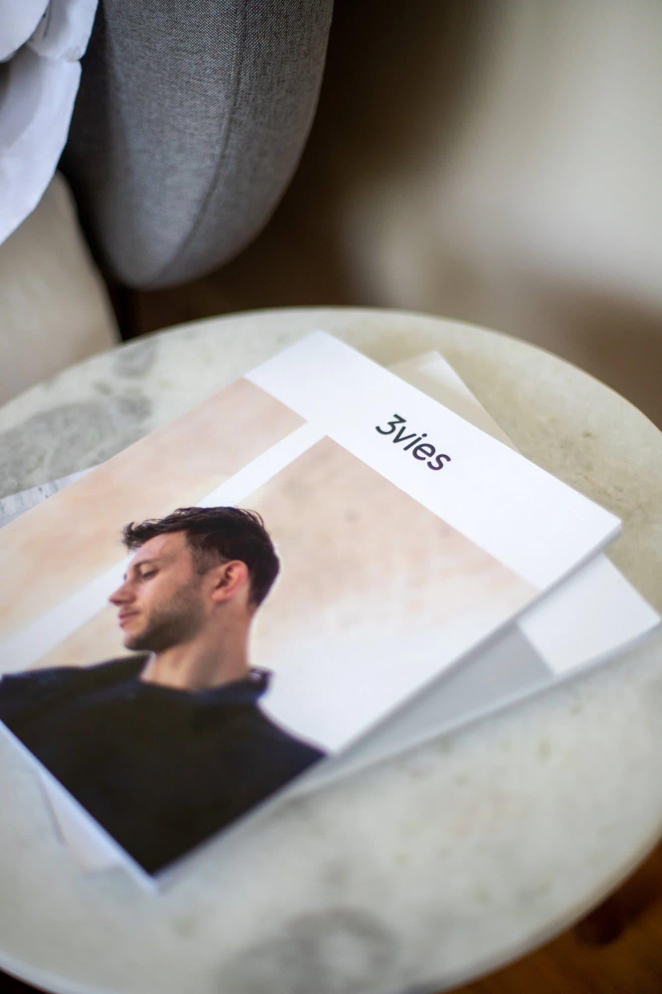 Printed copy of 3vies Volume 33 on a marble side table, its cover showing a man in profile.
