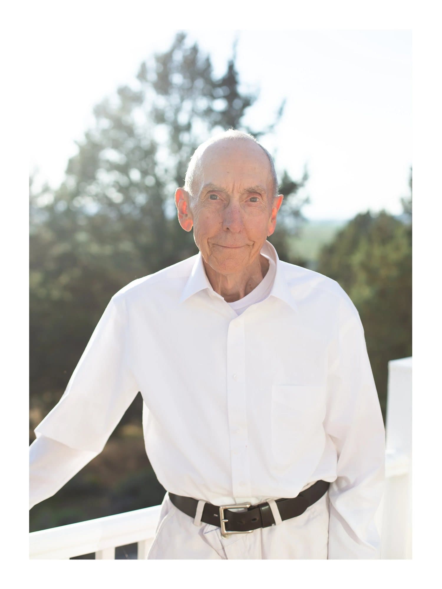 Mark's grandpa in a white shirt, smiling on a sunlit porch, TIMELESS print Grandpa.
