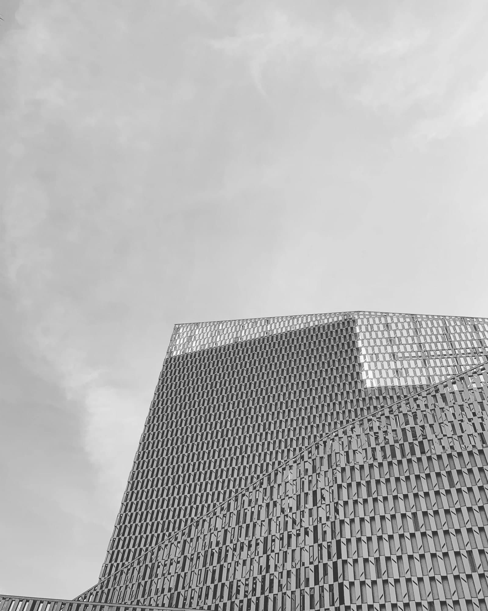 Black and white photo handout of a modern building's patterned facade against a cloudy sky.
