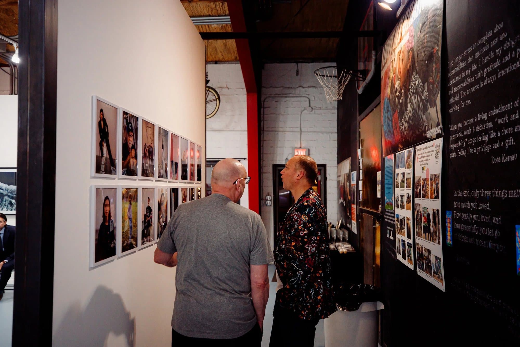 Two visitors study the People Who Inspire Me portrait wall at 1906 Gallery.