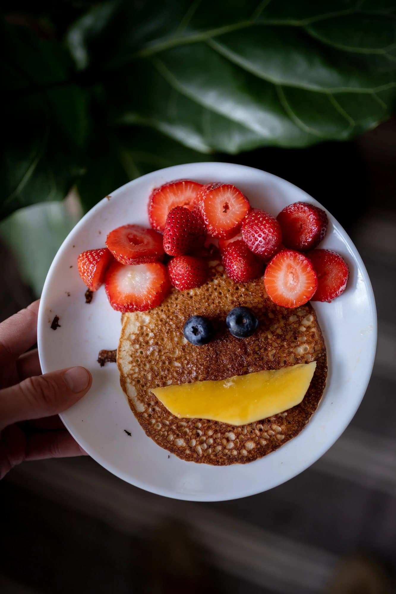A pancake face with strawberry hair, blueberry eyes and a mango smile.