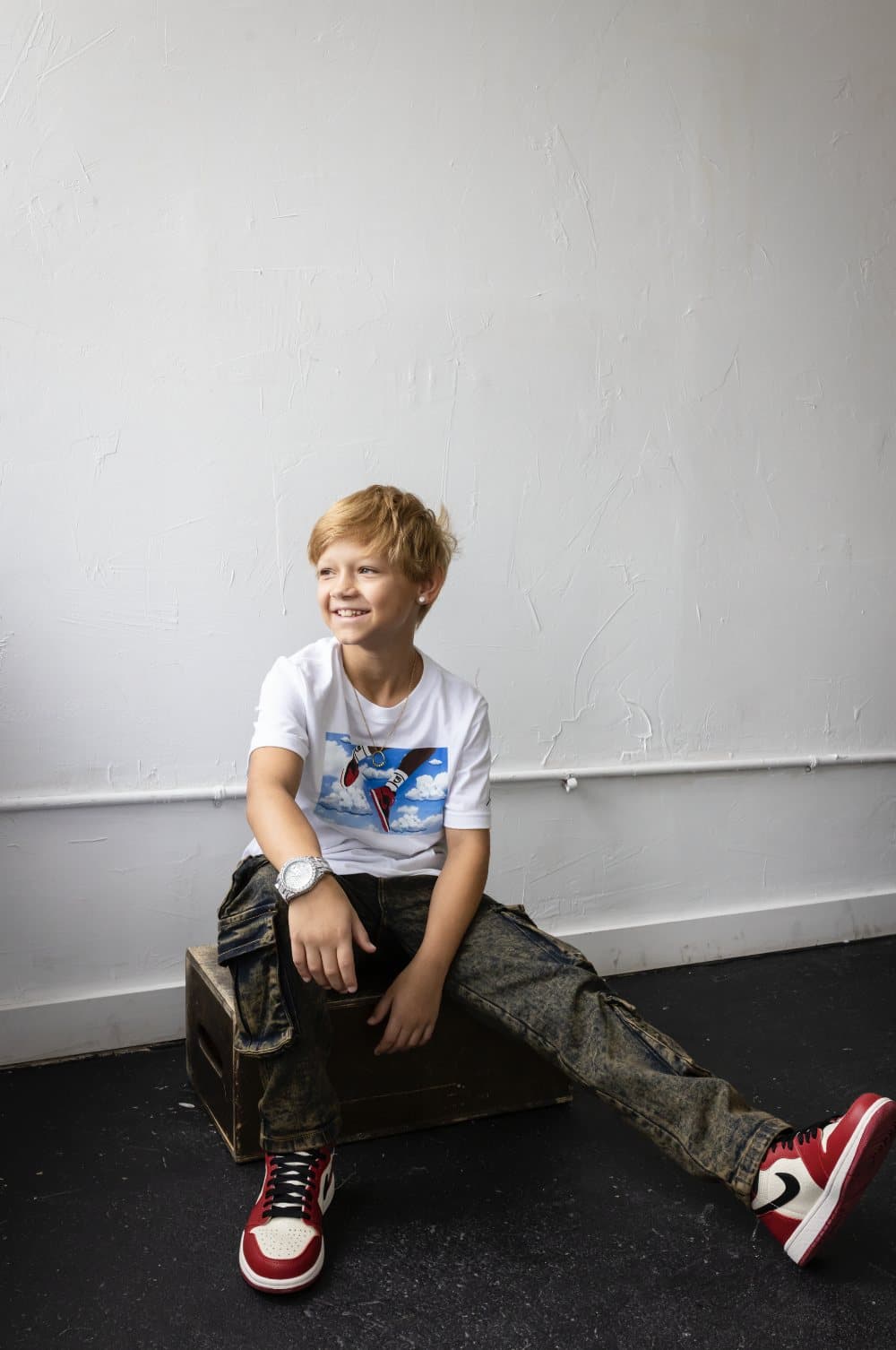 Luca Warnick, featured in Volume 40, smiling on a wooden crate in a white studio.