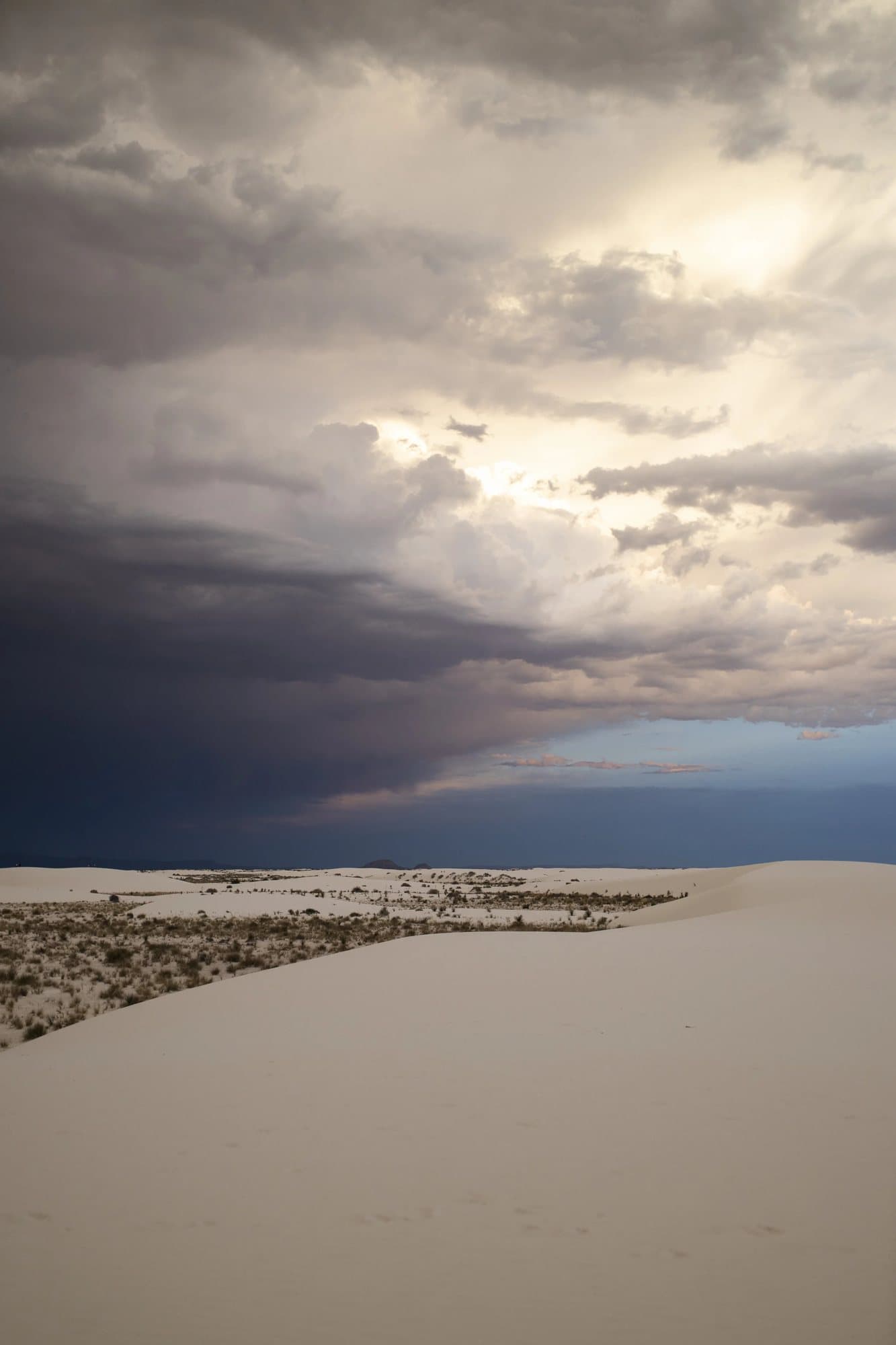Storm clouds breaking over pale White Sands dunes, an example of the volume's photography.