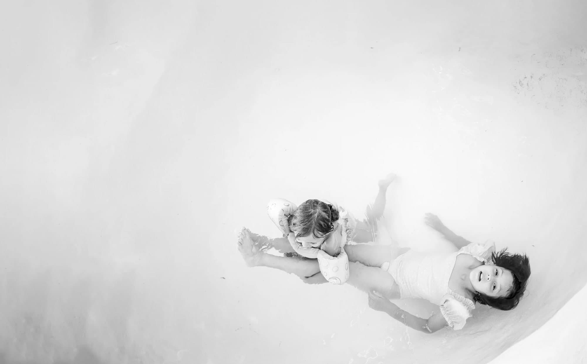 Spread from Volume 36 of two young girls lying laughing on a white floor, in black and white.